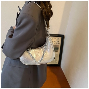 Détail du sac demi-lune argenté métallisé matelassé avec une grosse chaîne en métal
