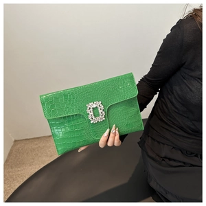 Close-up of green crocodile-embossed leather clutch with a square crystal buckle