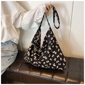 Detail shot of a black tote bag with beige bow patterns on high-quality canvas fabric