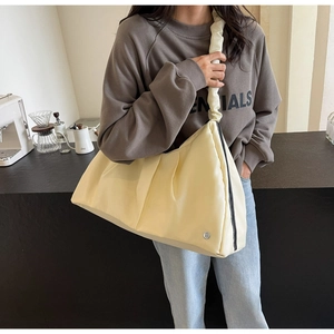 Dettaglio di una borsa a tracolla giallo crema con pieghe in tessuto minimaliste