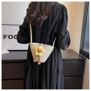 Close-up of woven crossbody bag with yellow sunflower detail and pearl button closure