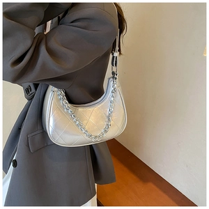 Détail d'un sac demi-lune argenté matelassé avec finition métallisée et chaîne