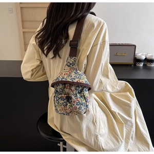 Close-up of vintage floral brocade crossbody bag with drawstring closure and brown strap