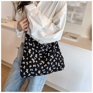 Detail shot of black tote bag with white bow pattern worn by a model in a home setting