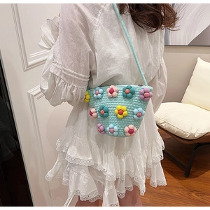 Close-up of a light blue woven crossbody bag with colorful 3D floral decorations