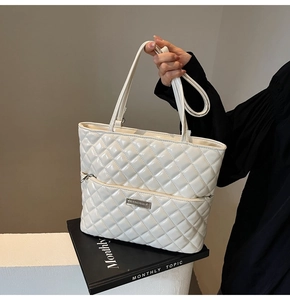 Close-up of white quilted PU leather handbag with glossy finish and metal logo plate