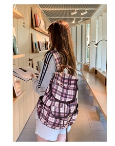 Detail view of plaid nylon backpack featuring a pink and brown check pattern and front pockets