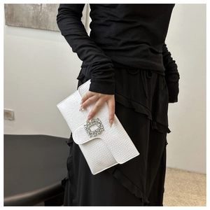 Detail of white PU clutch with crocodile texture and large square crystal buckle
