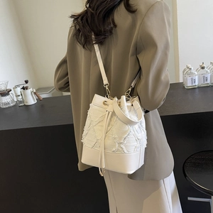 Chic white denim quilted bucket bag with fringe texture and smooth leather base for women