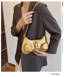 Detail of golden Y2K shoulder bag with metallic studs and heart buckle decoration