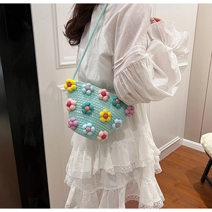 Detail of crossbody straw bag featuring 3D colorful felt flowers and woven texture