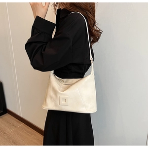 Detail view of cream PU leather crossbody bag with quilted stitching on model