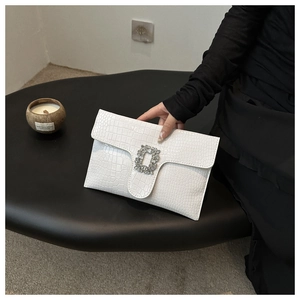 Detailed macro view of white faux crocodile leather clutch with square rhinestone buckle