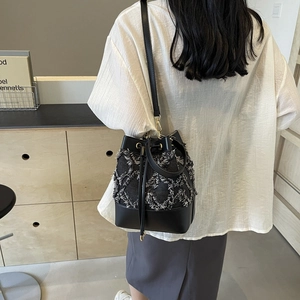 Denim quilted bucket bag in black with drawstring closure and golden hardware