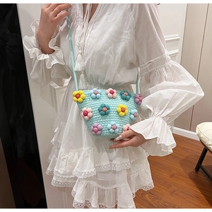 Detail of light blue woven crossbody bag featuring colorful 3D plush flower decorations