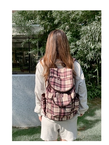 Pink and brown checkered nylon backpack shown on model back against a nature background