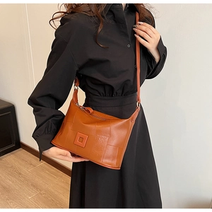 Close-up of brown PU leather crossbody bag with square buckle on a female model