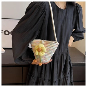 Macro detail of handwoven bag with colorful wave patterns and a yellow floral pearl accent