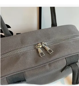 Detailed close-up of smooth dual metal zippers on a gray canvas handbag