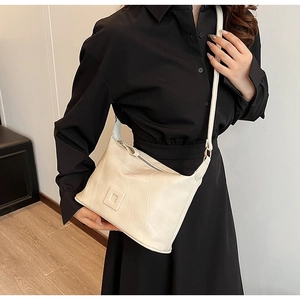 Detail showing geometric patchwork design on an off-white PU leather shoulder bag