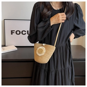 Detail of woven straw bucket bag with a daisy flower and white pearl button closure