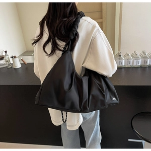 Dettaglio di una borsa a tracolla nera capiente con tracolla a nodo e design plissettato