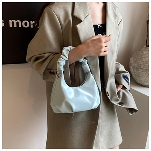 Detail of light blue PU leather handbag with scrunchie handle and pleated bottom design