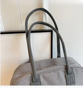 Detailed macro view of the sturdy silver dual zipper closure on a gray canvas tote bag