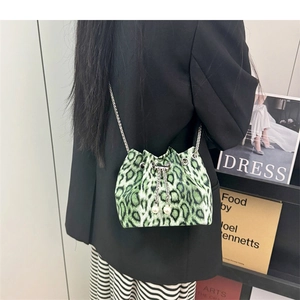 Green leopard bucket bag with chain strap and pearl drawstring on model's shoulder