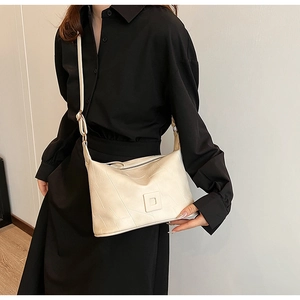 Detail view of cream PU leather crossbody bag with geometric texture and slim shoulder strap