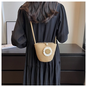 Detail of hand-woven straw bucket bag with white daisy flower and pearl clasp closure