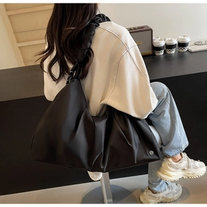 Vista dettagliata della borsa a nuvola nera oversize con finitura in nylon lucido e tracolla