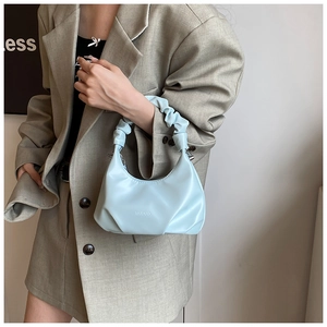 Detail of light blue PU leather scrunchie handbag with crescent shape and MUDUO logo