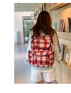 Red, white, and blue plaid nylon backpack with purple straps shown in a bookstore
