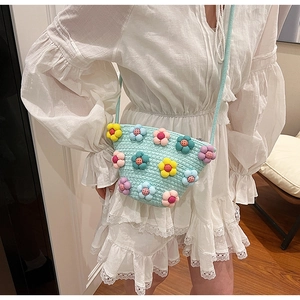 Close-up of light blue hand-woven crossbody bag featuring 3D colorful plush floral decor