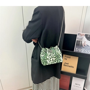 Detail of green leopard print bucket bag with elegant pearl charms and silver chain strap