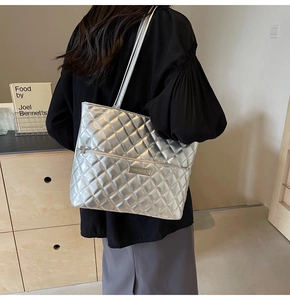 Detailed side view of silver quilted tote bag with metallic finish on model