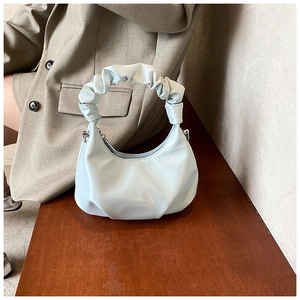 Detail of light blue PU leather crescent bag featuring a unique gathered ruched handle design