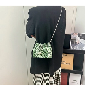 Detail of green leopard print bucket bag with silver chain strap and pearl drawstring