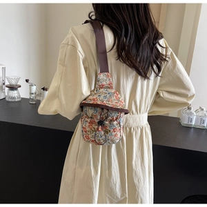 Detailed view of floral crossbody bag with drawstring closure and brown shoulder strap