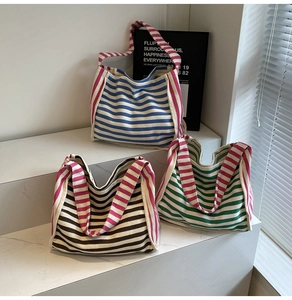 Three colorful striped knit tote bags on white stone steps with natural light