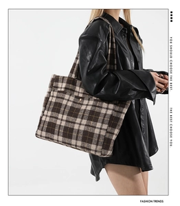 Détail d'un sac cabas à carreaux en laine avec bouton doré sur une robe en cuir noir