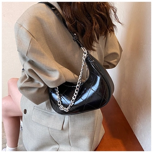 Détail d'un sac hobo noir en similicuir matelassé avec chaîne argentée sur modèle