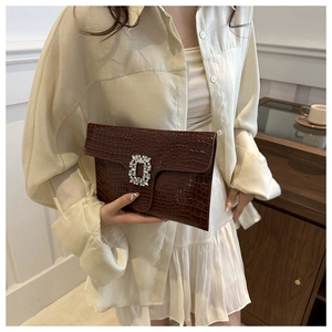 Close-up of a dark brown crocodile-embossed PU leather clutch with a square crystal buckle