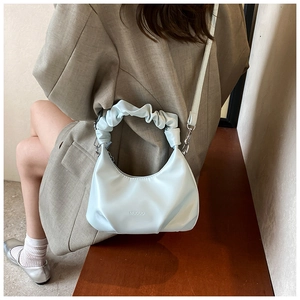 Detail view of light blue PU leather handbag with pleated cloud handle and adjustable strap