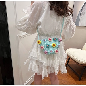 Detail view of woven mint green crossbody bag featuring colorful 3D knitted flower accents