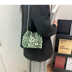 Detail view of green leopard print bucket bag with metal chain and pearl drawstring