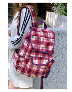 Detail of red and white plaid nylon backpack with purple straps and side pockets