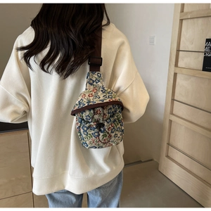 Back view of a mini floral jacquard crossbody bag with adjustable strap on a model