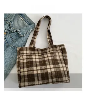 Détail du sac cabas en laine à carreaux marron avec boucle magnétique dorée et bandoulière